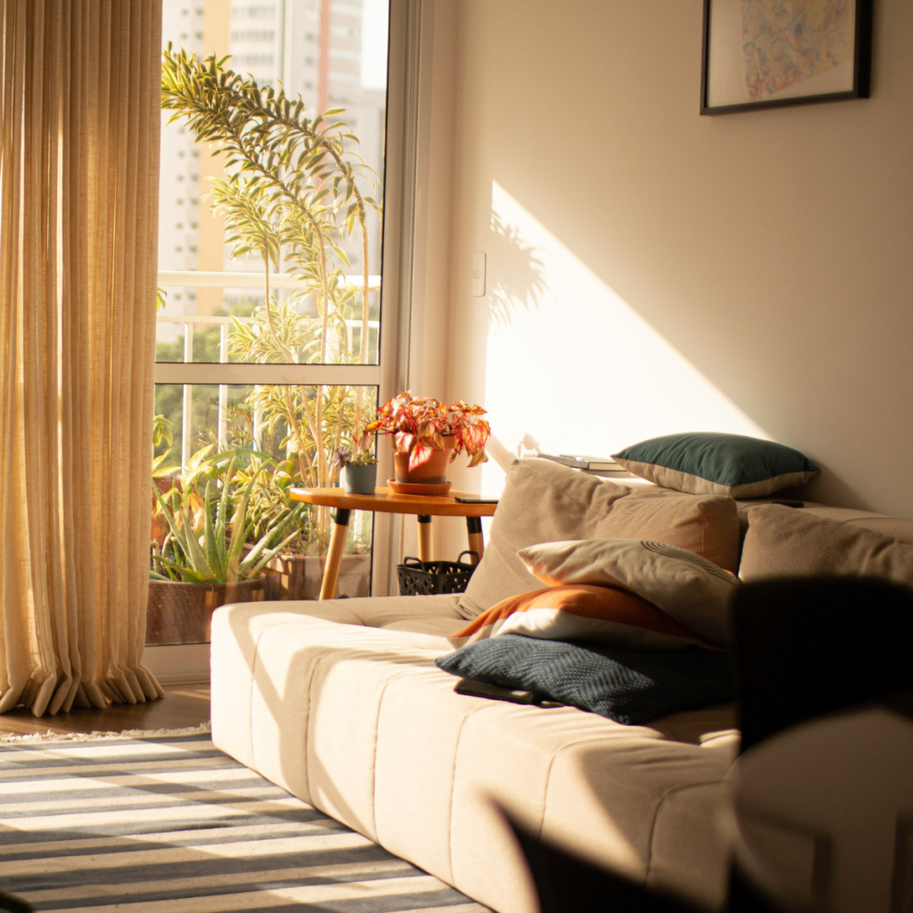 bright sunlit living room with neutral tones, sofa, and natural light through large window