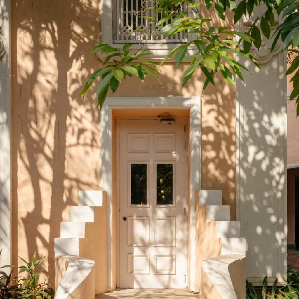 Colonial doorway with dappled tree shadows on warm peach walls, suggesting the threshold between learned behaviour and nervous system response