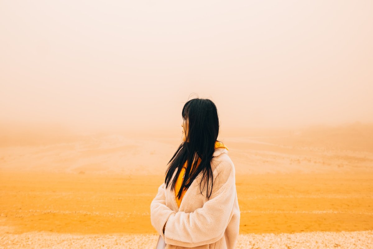 Is it my personality or my nervous system? A woman looking out over a hazy golden landscape. Tidylodge Singapore.