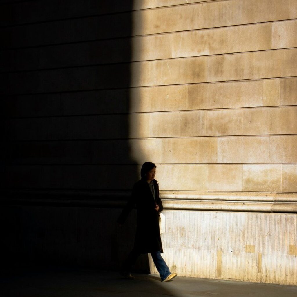 Woman walking through deep shadow toward light, illustrating the mental habit of preparing for the worst